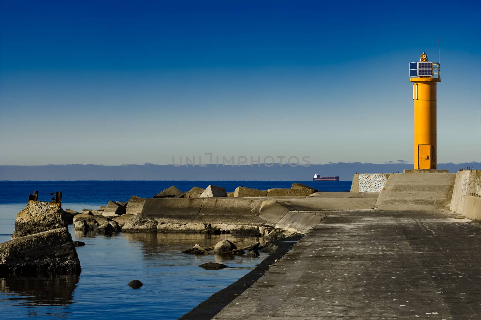 Yellow lighthouse on breakwater dam by sengnsp