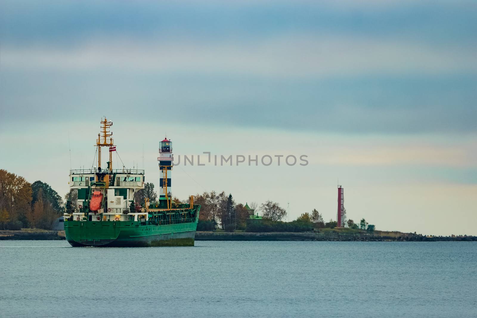 Green cargo ship moving to the port in cloudy day