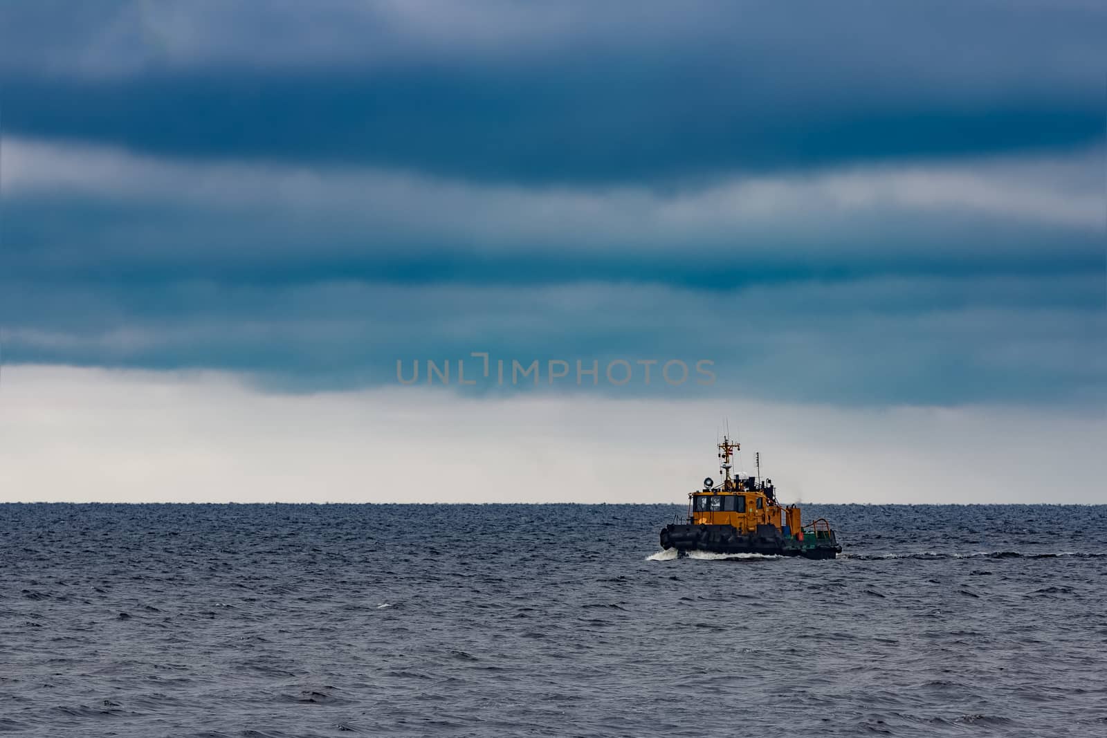 Small orange tug ship moving from the Baltic sea