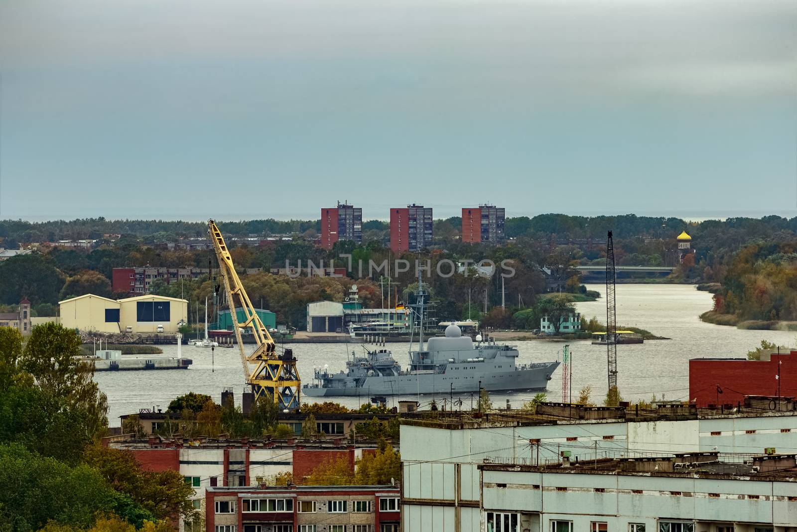 Military ship sailing past the cargo port in Riga, Latvia