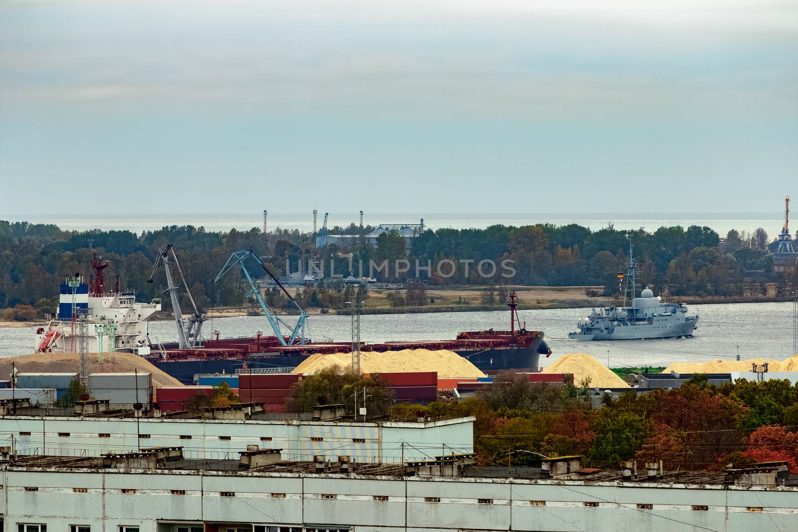 Military ship sailing past the cargo port in Riga, Latvia