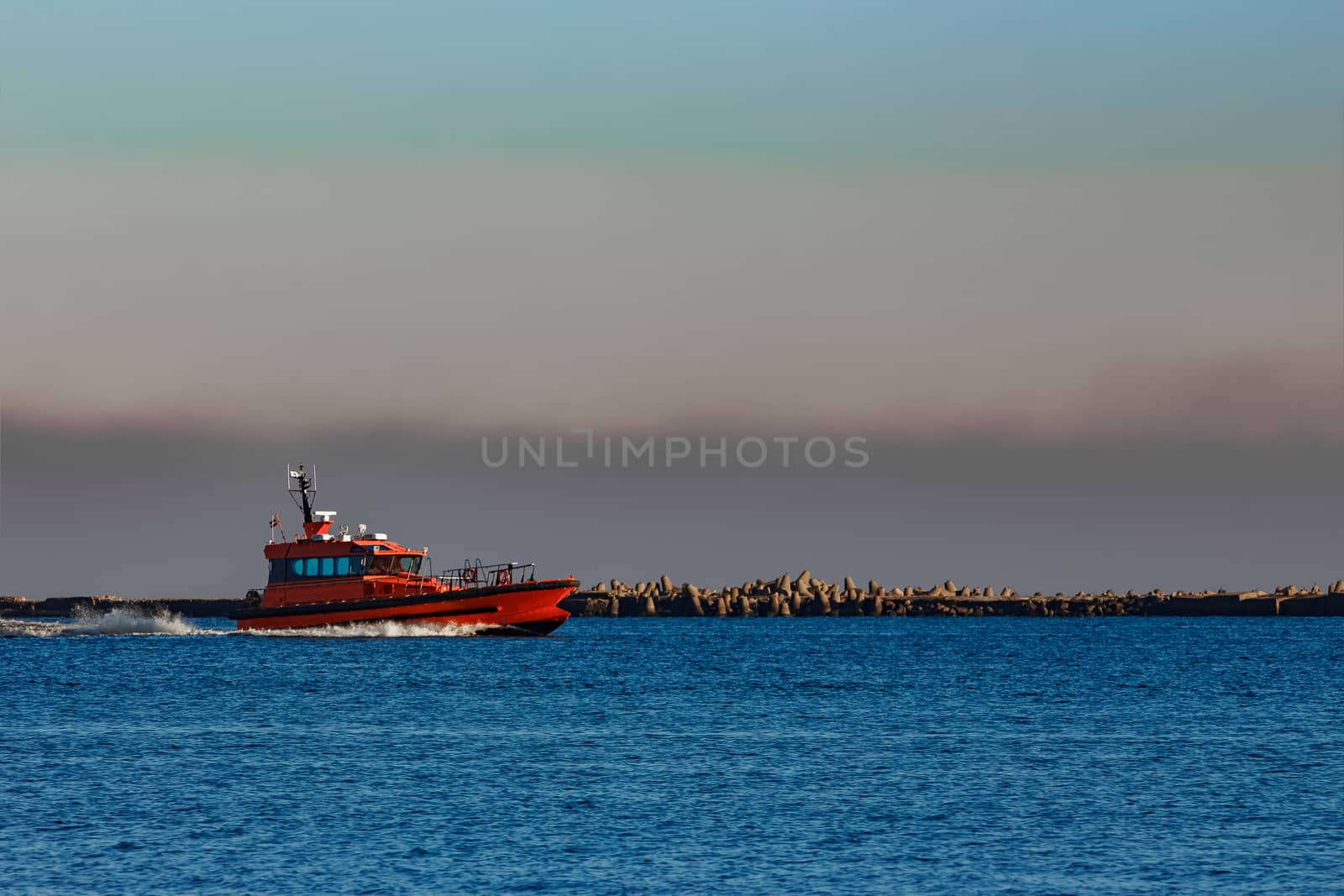 Red pilot ship moving past the breakwater dam in Riga, Europe