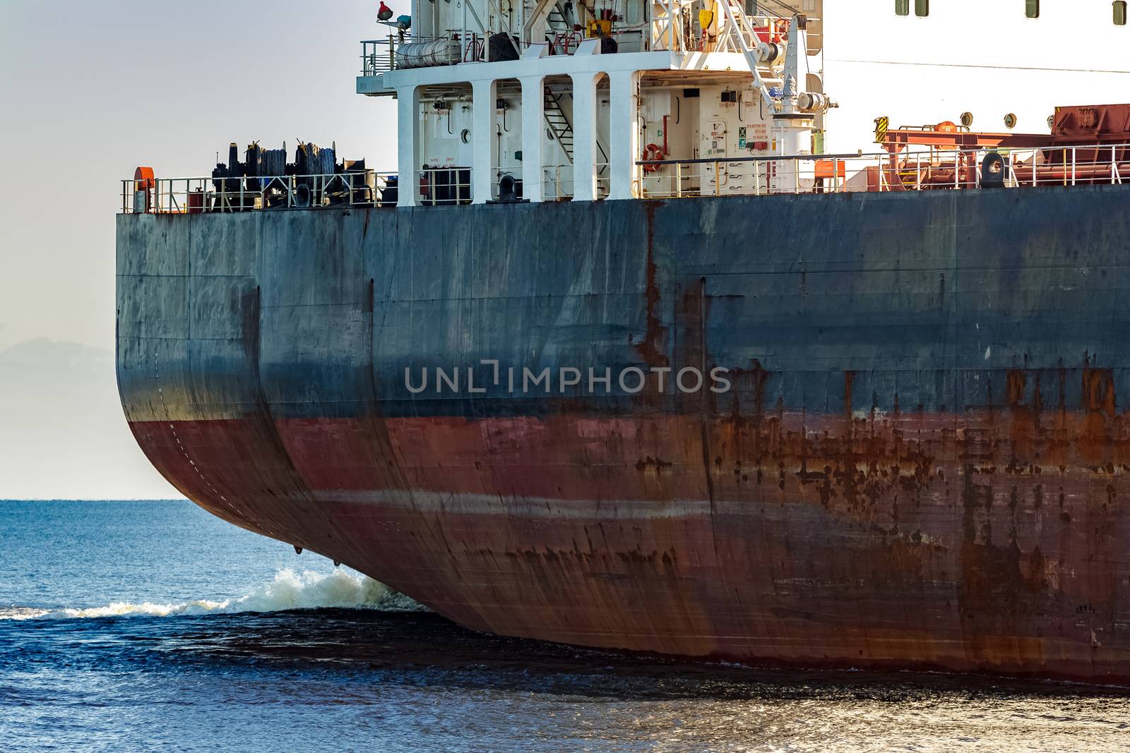 Black cargo ship's stern in still water close up. Riga, Europe