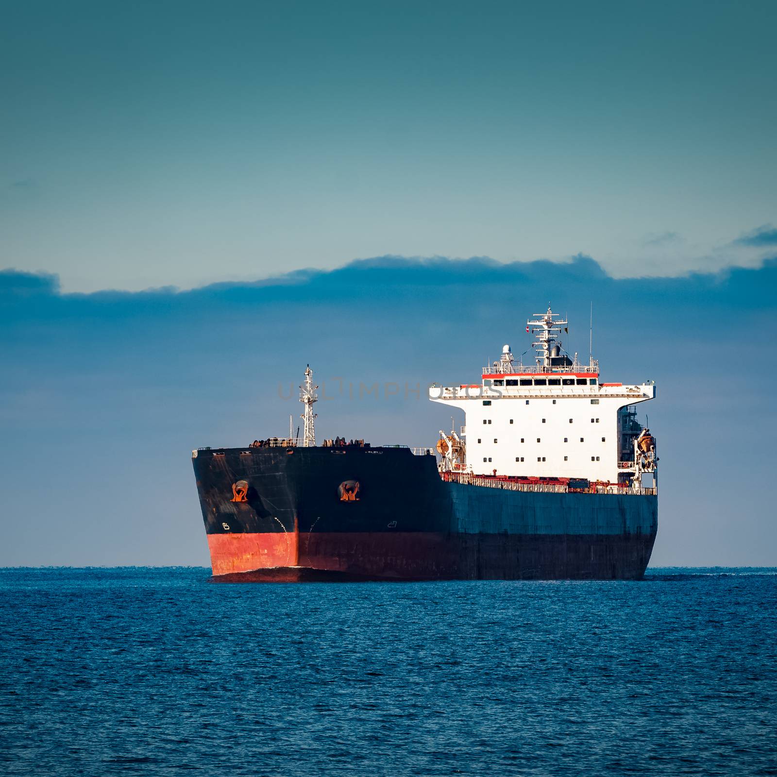 Black cargo ship moving in still Baltic sea water. Riga, Europe