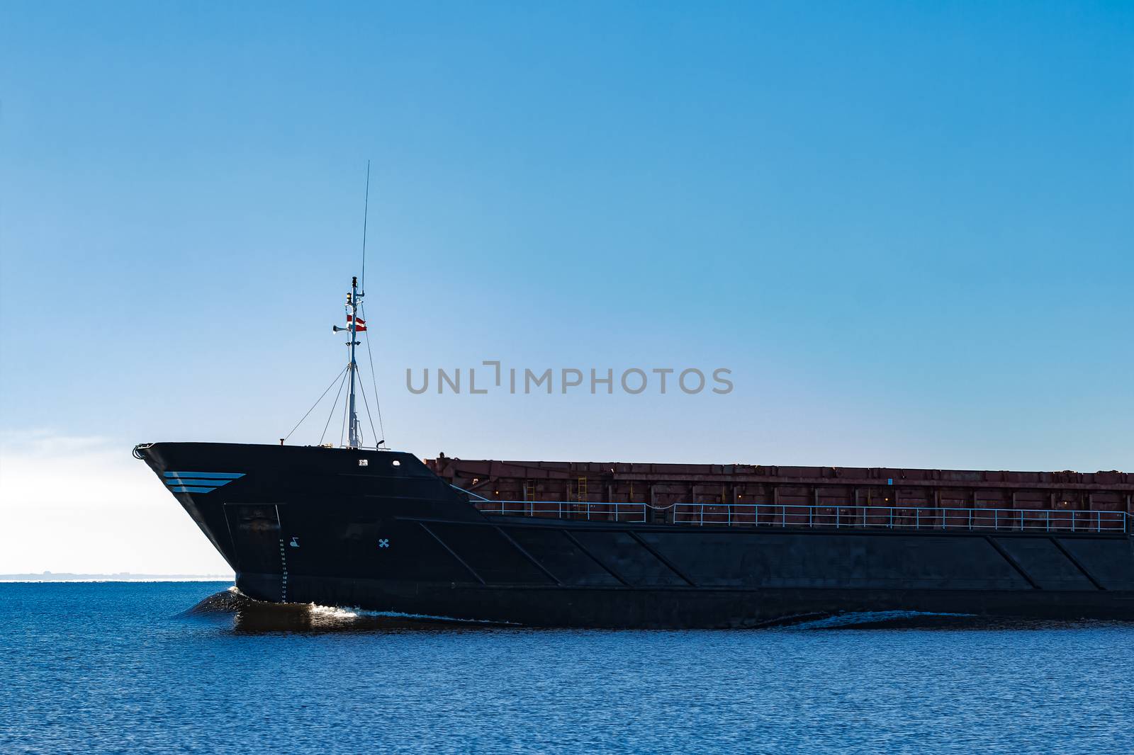 Black cargo ship's bow. Bulk carrier sailing in still Baltic sea