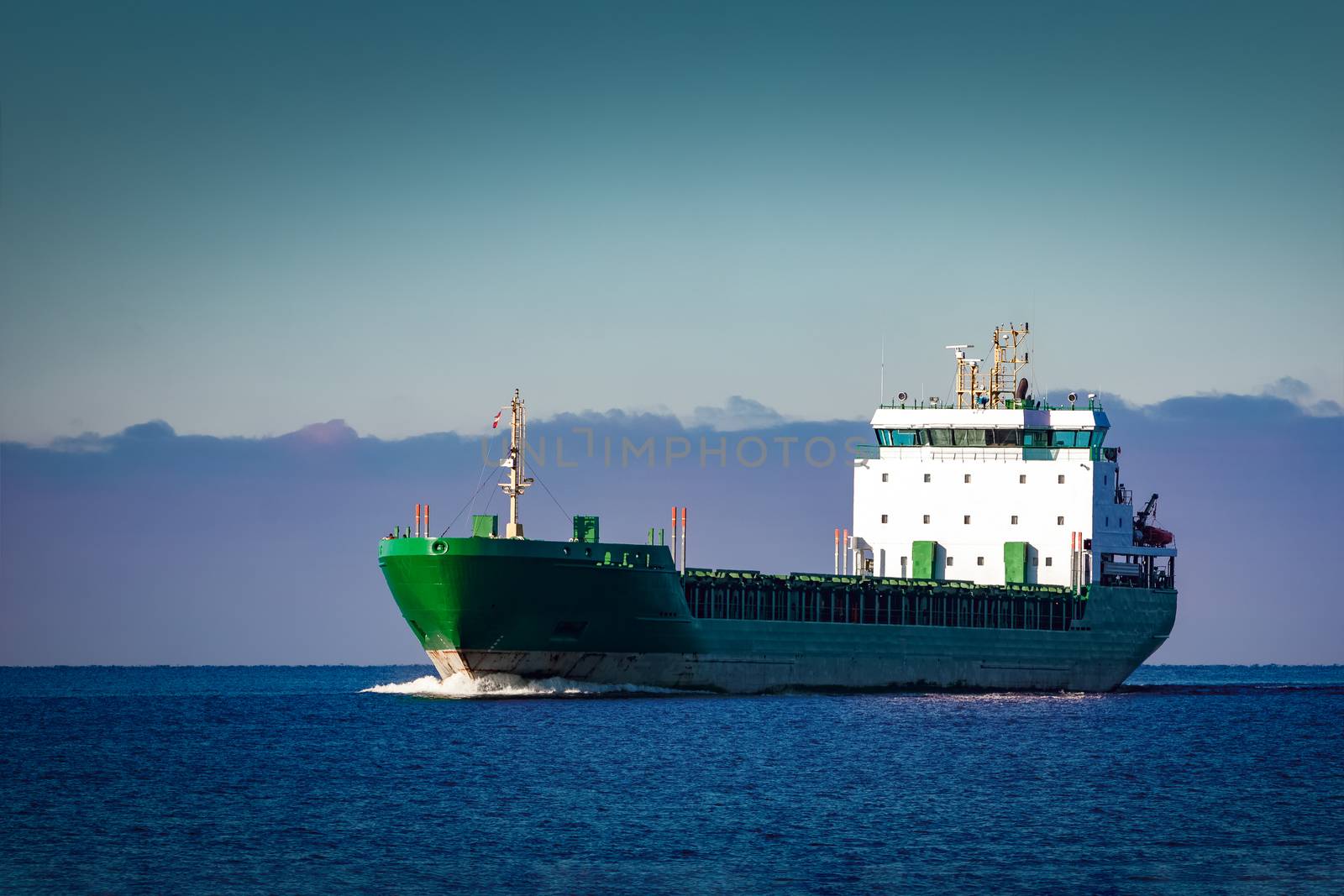 Green cargo ship moving in still water of Baltic sea