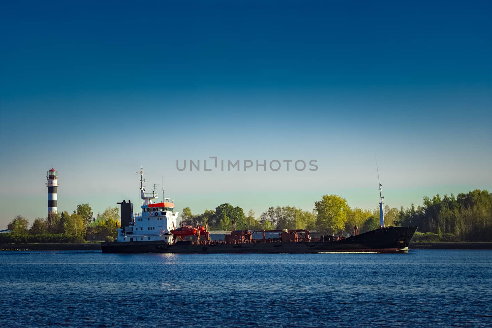 Black cargo oil tanker entering the port of Riga at sunny day