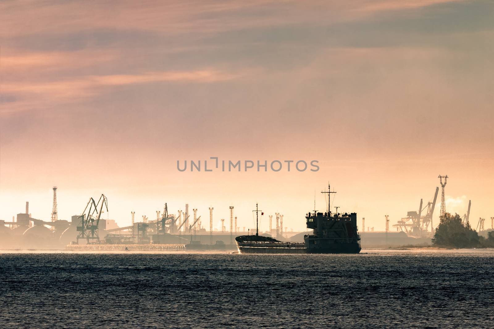 Cargo ship silhouette entering a port of Riga at the morning