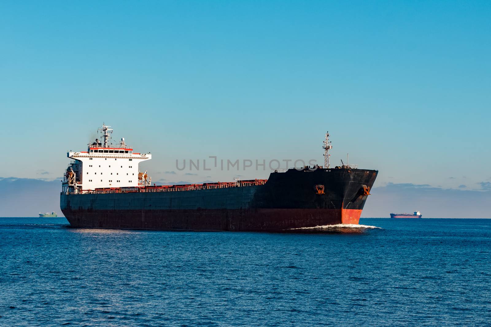 Black cargo ship moving in still Baltic sea water. Riga, Europe