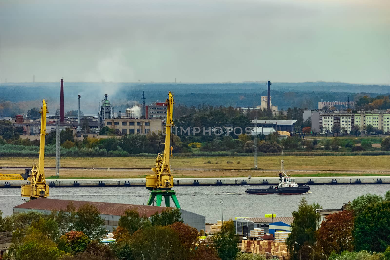 Tug ship moving past the cargo port at Riga city