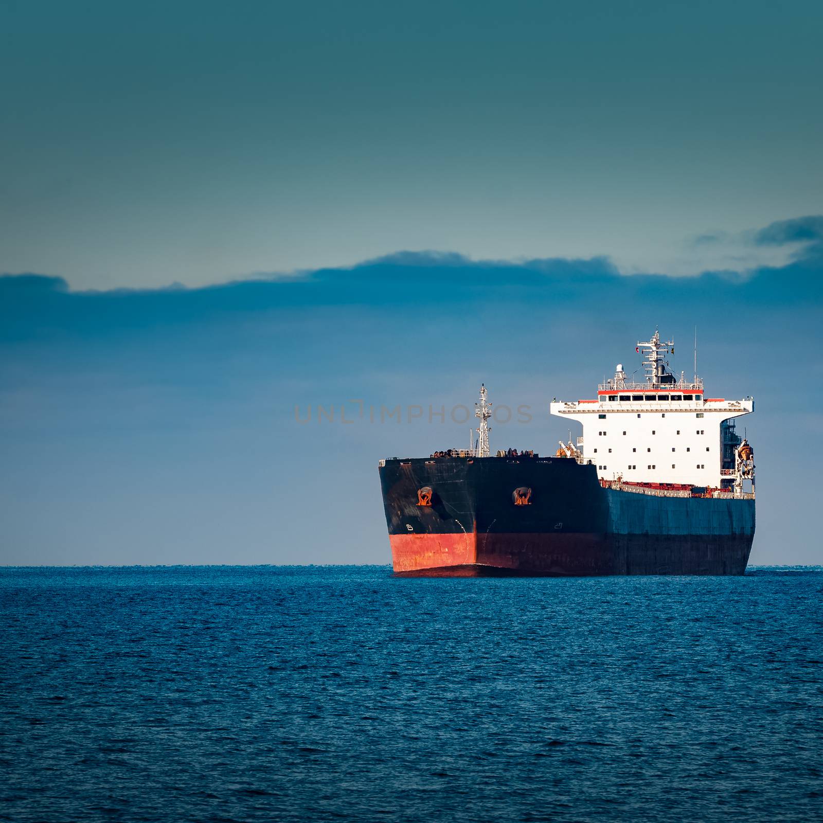 Black cargo ship moving in still Baltic sea water. Riga, Europe