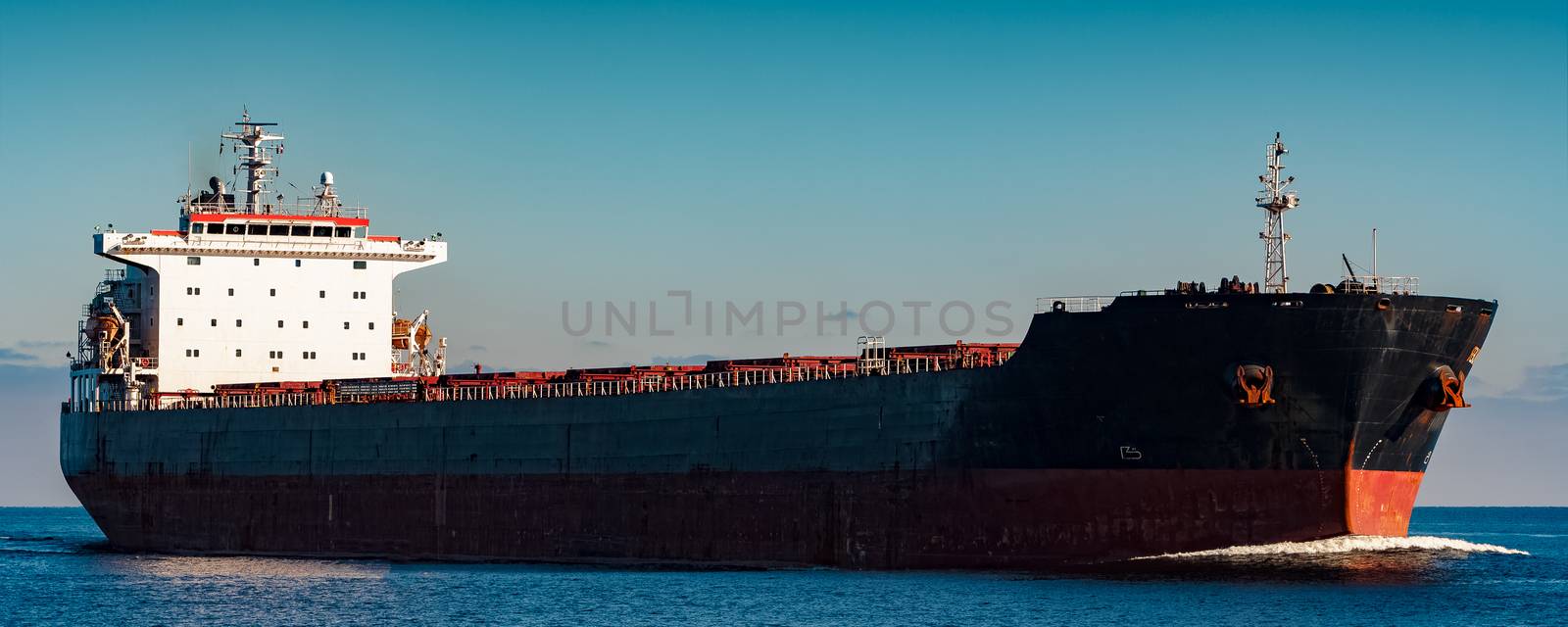 Black cargo ship moving in still Baltic sea water. Riga, Europe