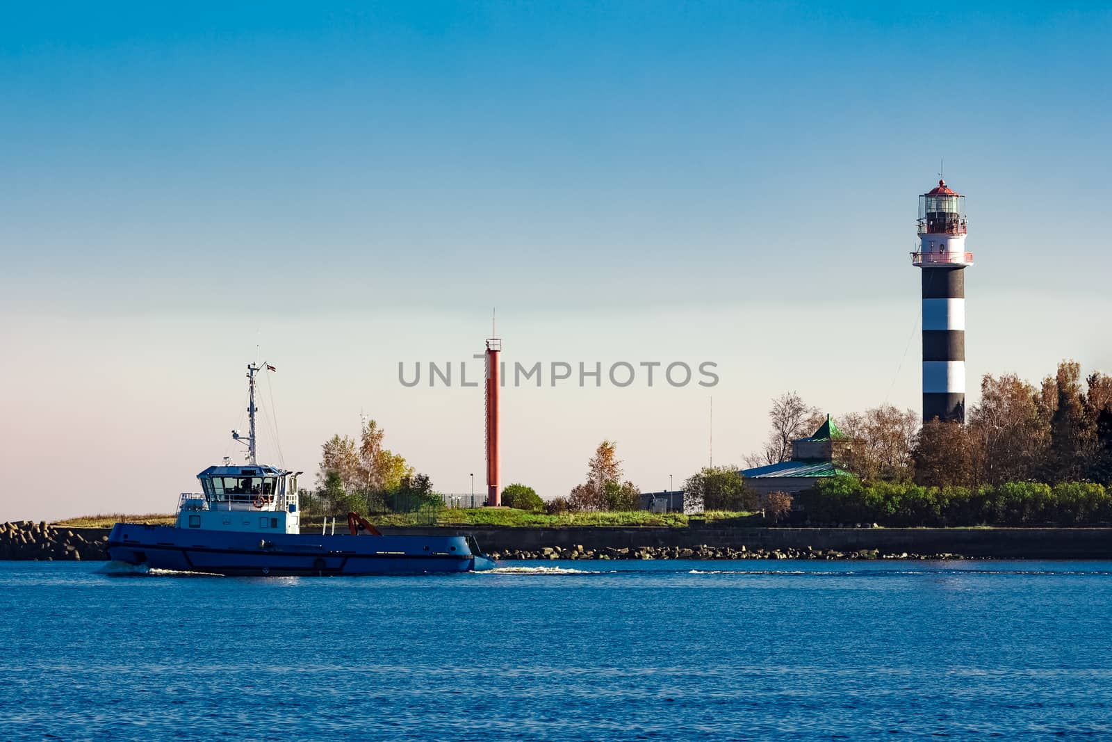 Blue small tug ship leaving Riga and entering the Baltic sea