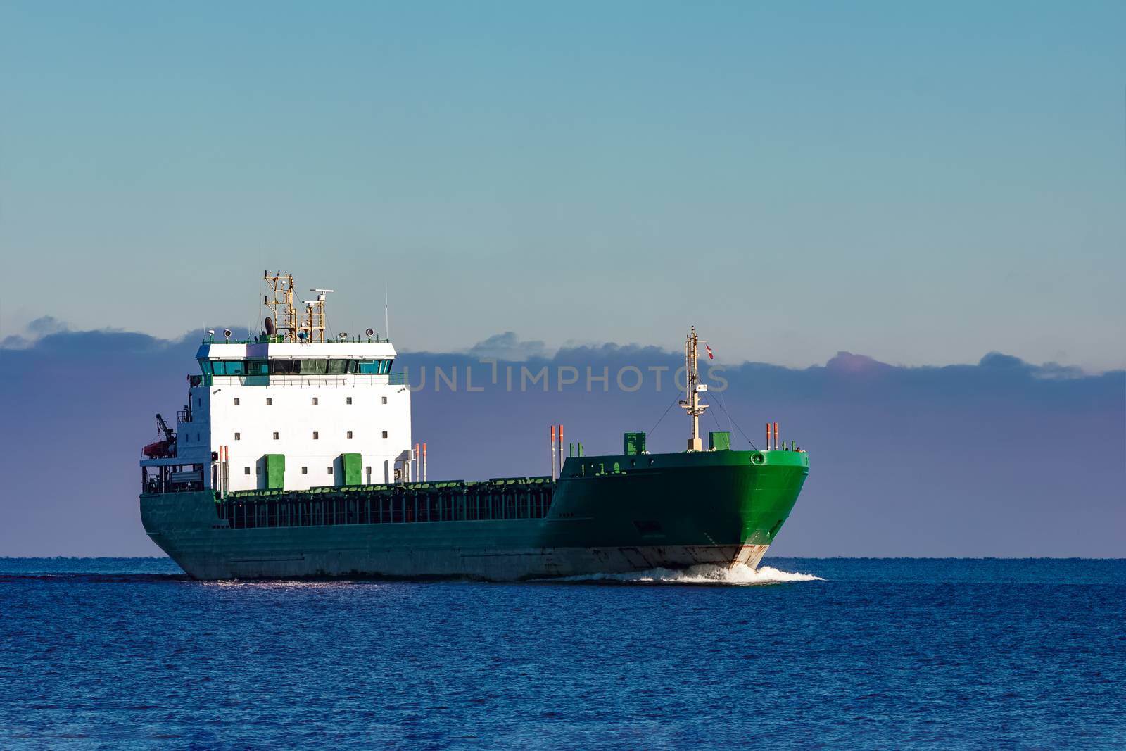 Green cargo ship moving in still water of Baltic sea