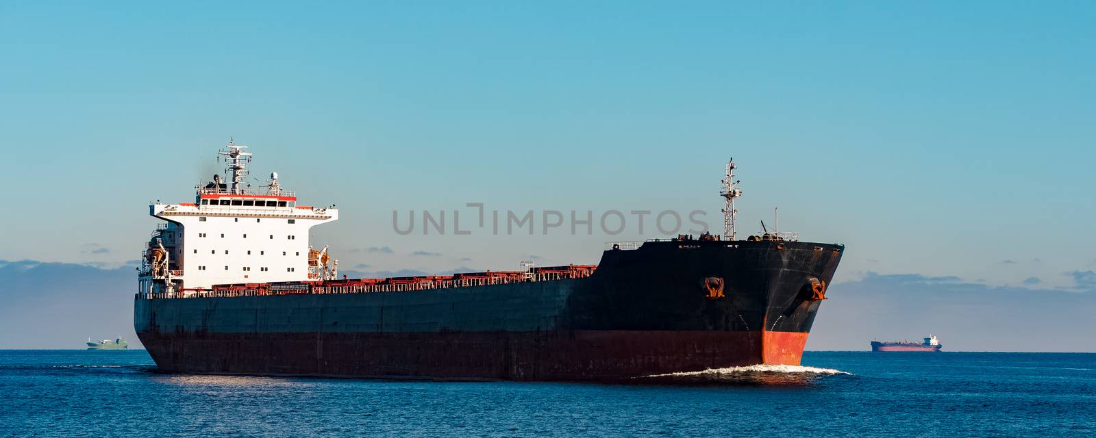 Black cargo ship moving in still Baltic sea water. Riga, Europe