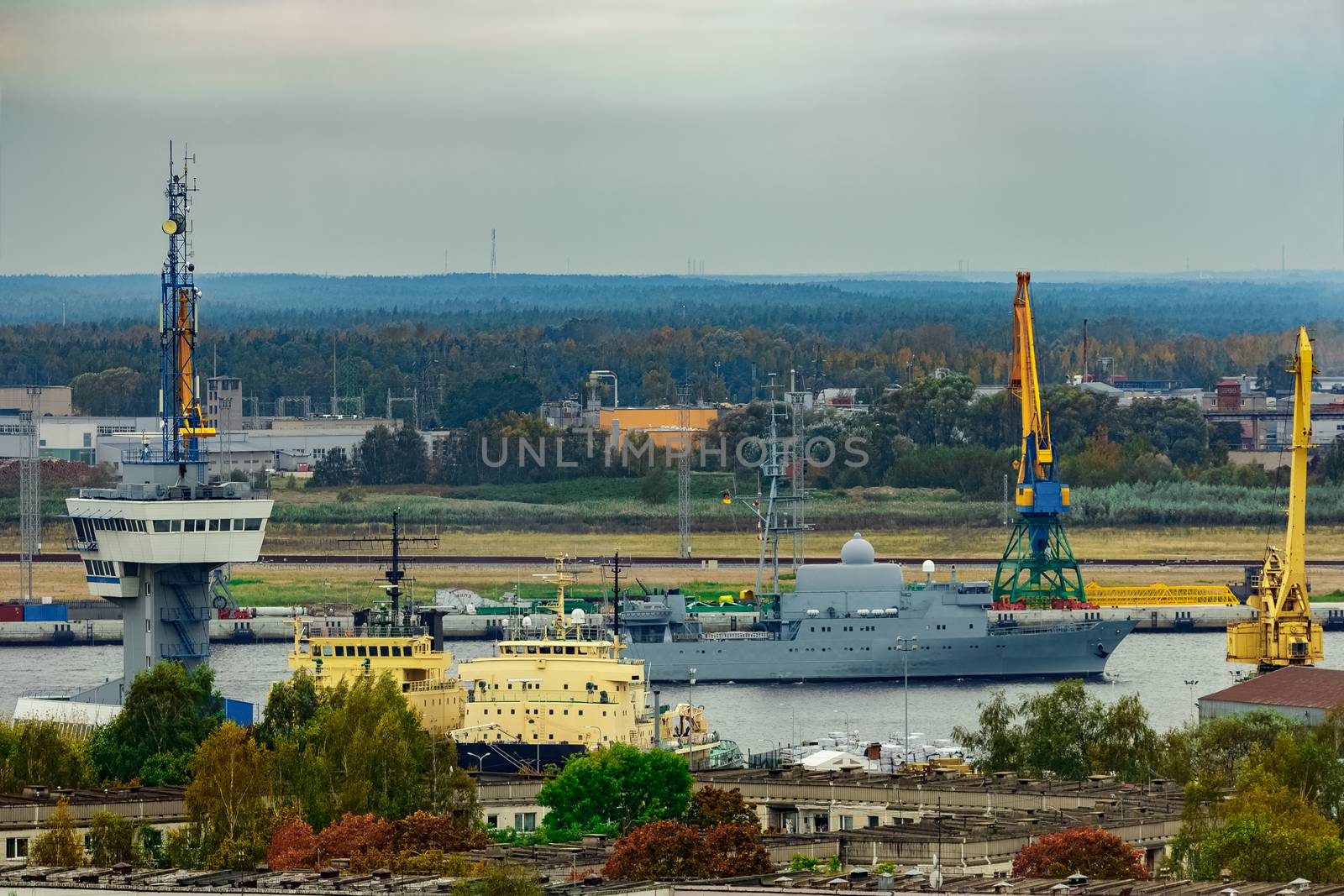 Military ship sailing past the cargo port in Riga, Latvia