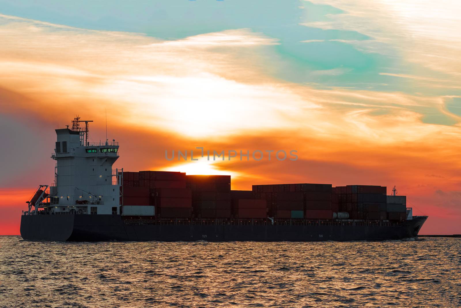 Blue container ship leaving Riga city during hot sunset