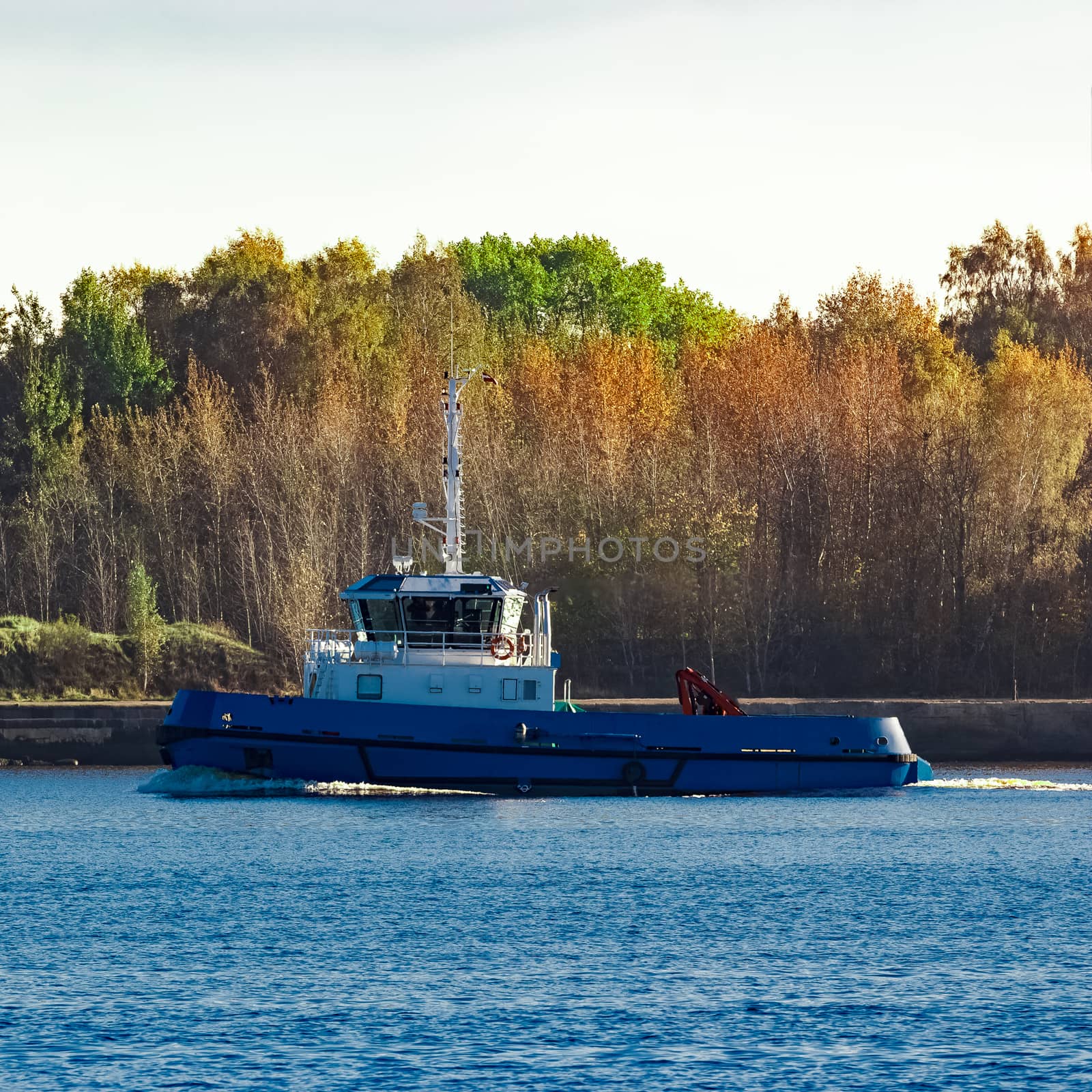 Blue small tug ship leaving Riga and entering the Baltic sea