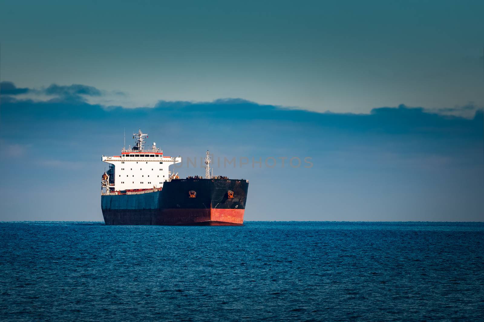 Black cargo ship moving in still Baltic sea water. Riga, Europe