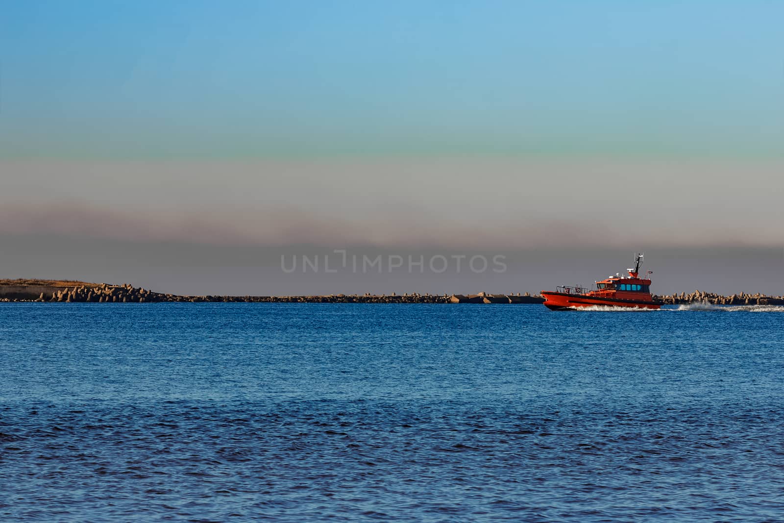 Red pilot ship moving past the breakwater dam in Riga, Europe