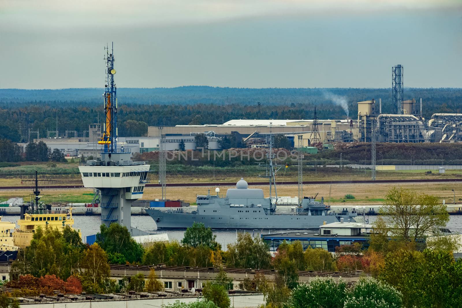 Military ship sailing past the cargo port in Riga, Latvia