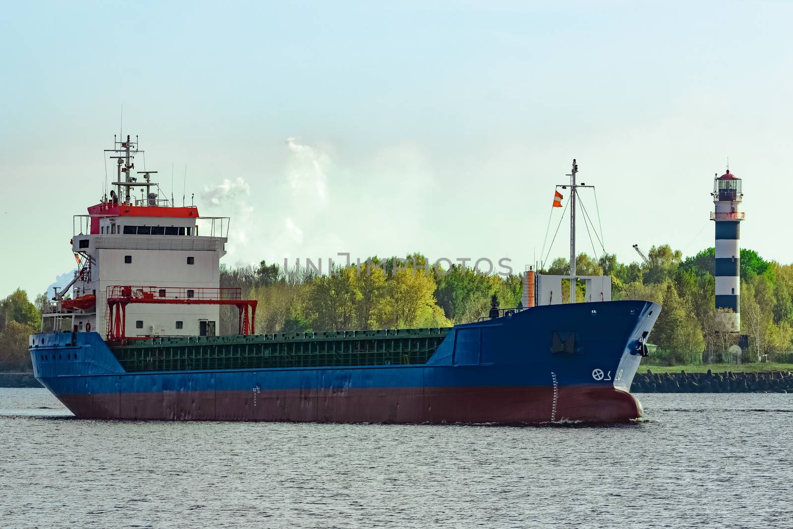 Blue cargo ship leaving the port of Riga at sunny day