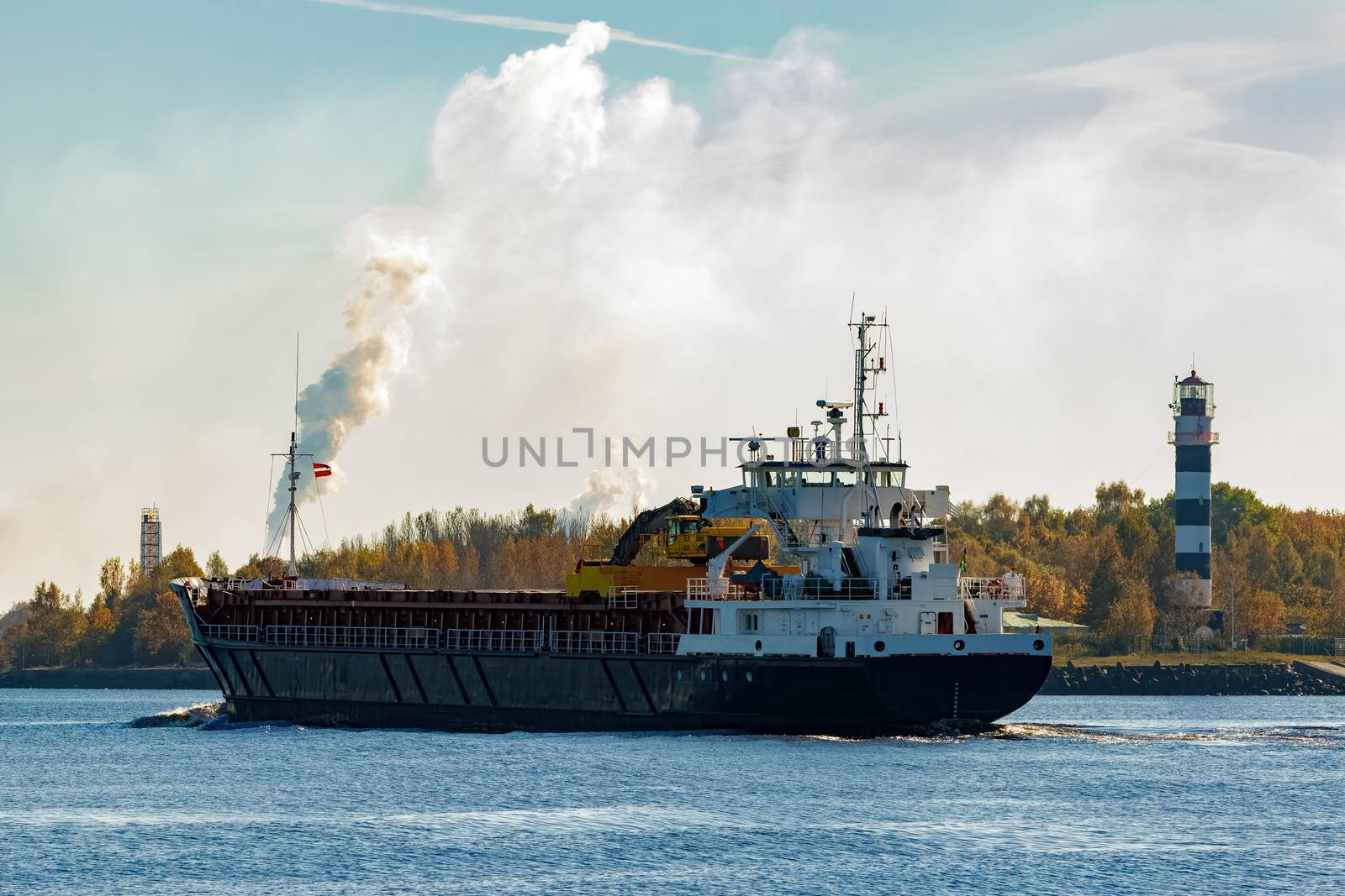 Black cargo ship with long reach excavator moving by Baltic sea