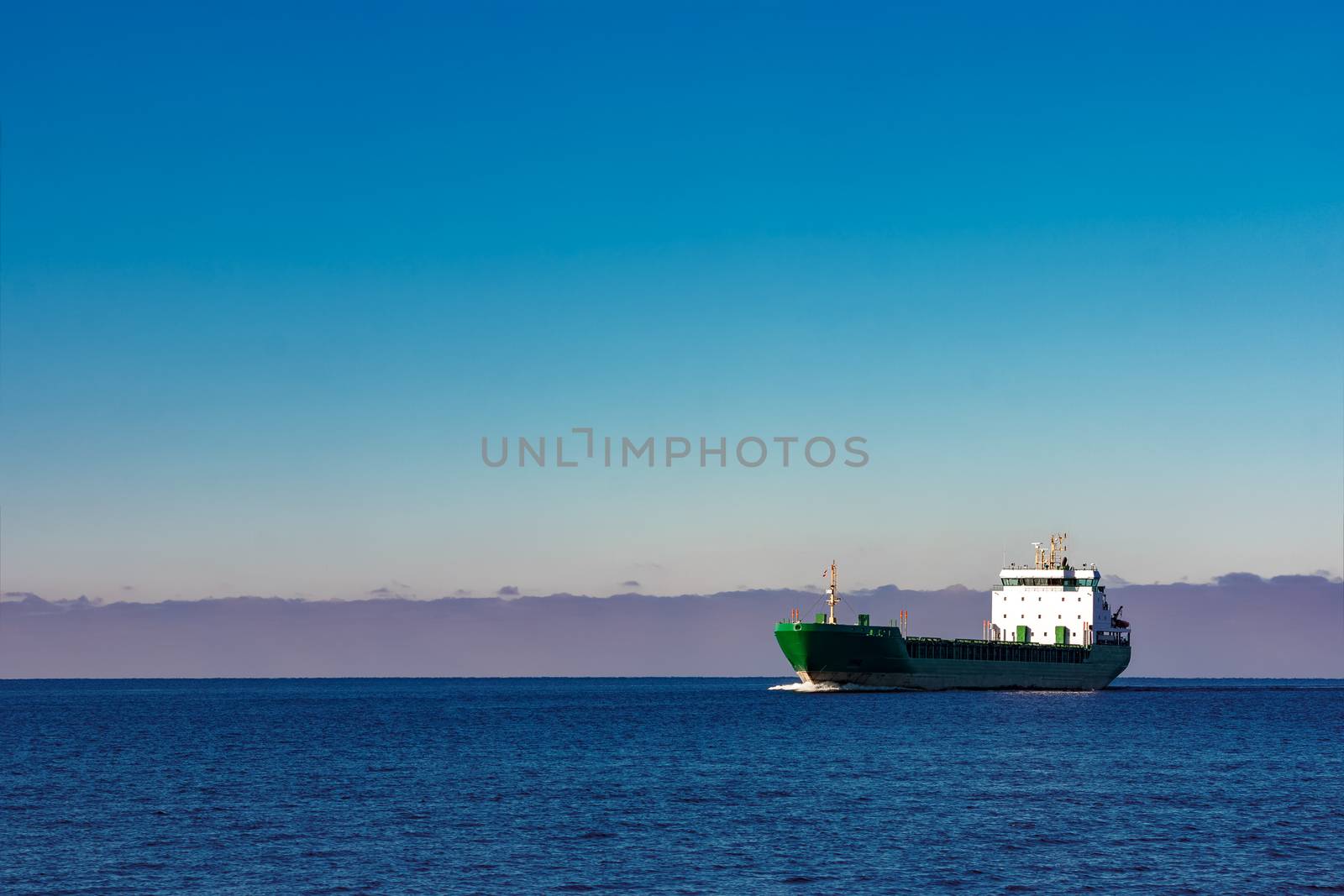 Green cargo ship moving in still water of Baltic sea