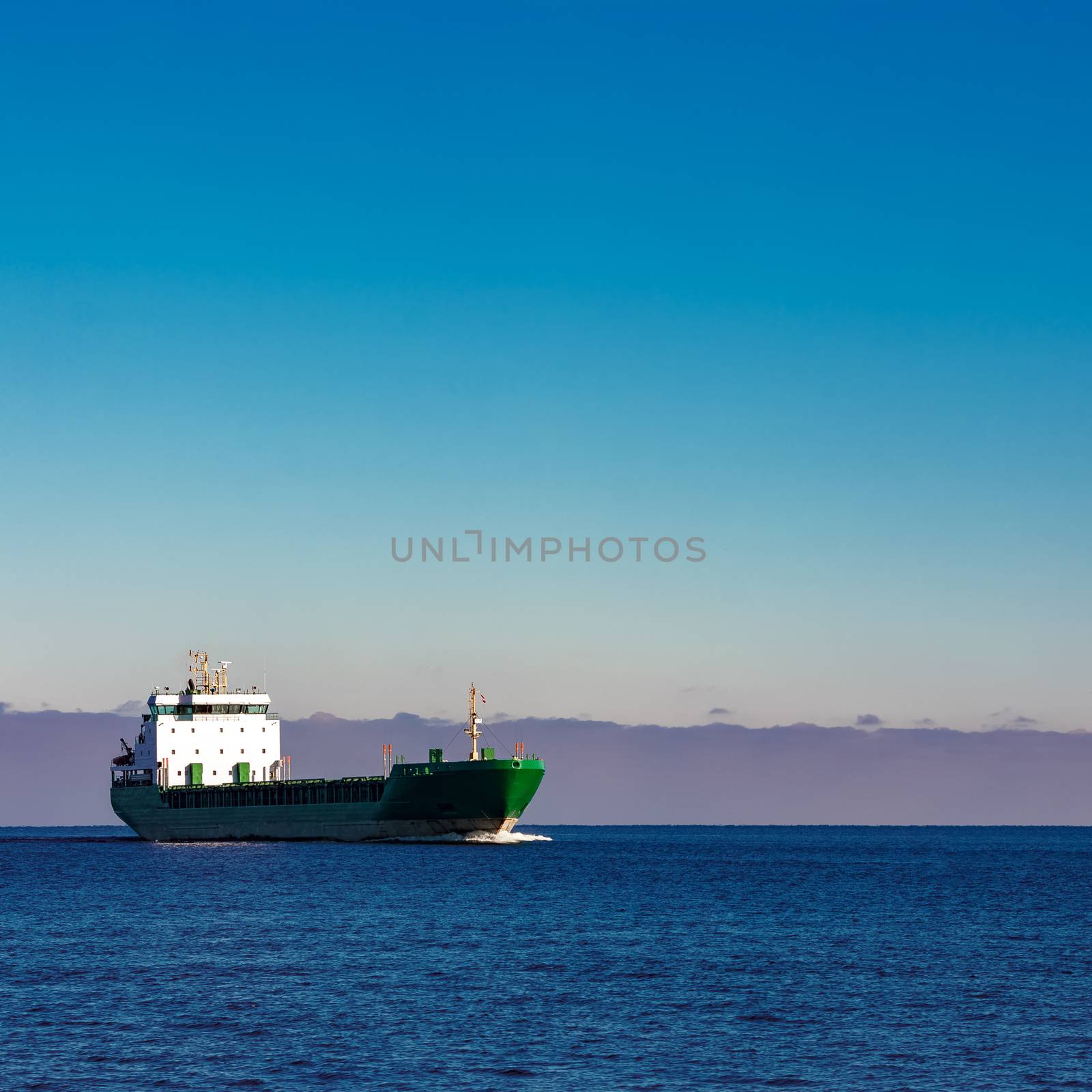 Green cargo ship moving in still water of Baltic sea