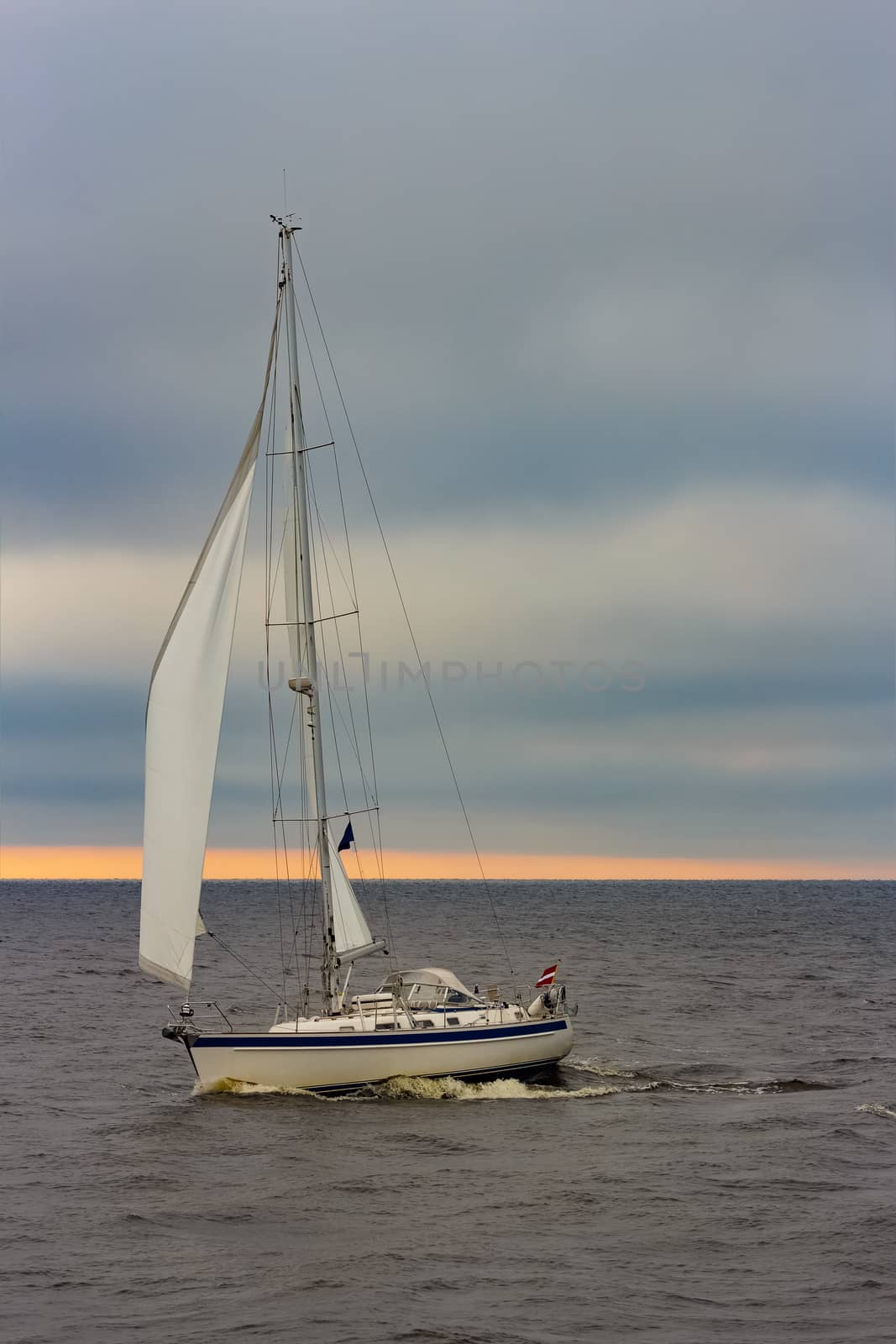 White sailboat traveling in Baltic sea in cloudy day