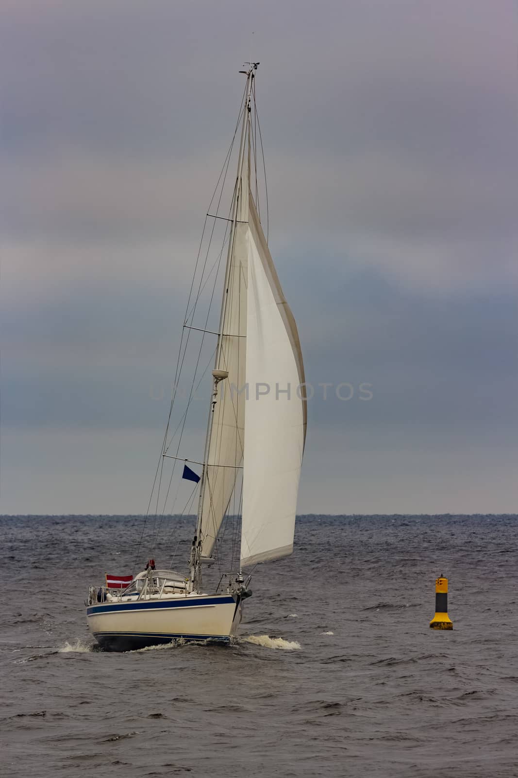 White sailboat traveling in Baltic sea in cloudy day