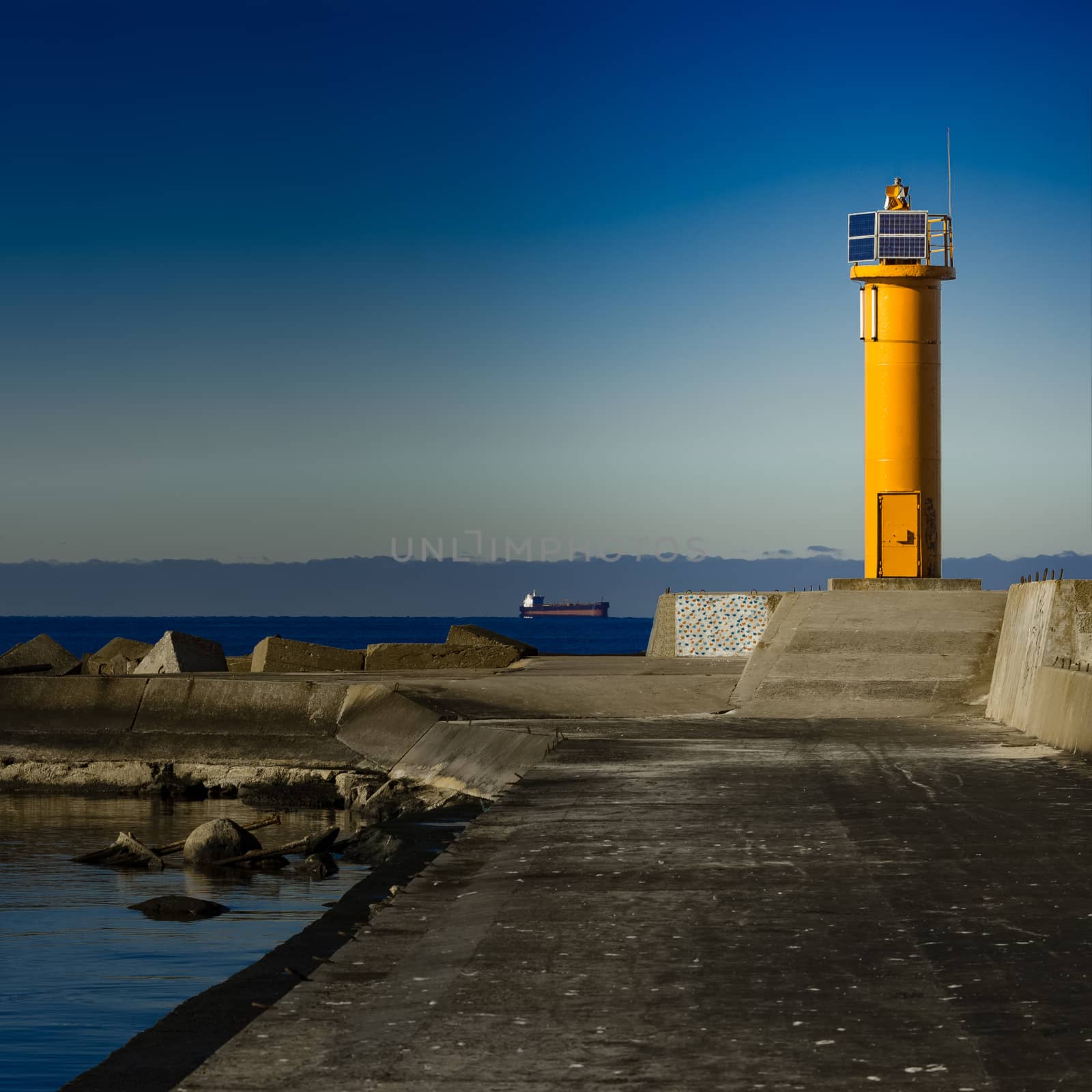 Yellow lighthouse on breakwater dam by sengnsp