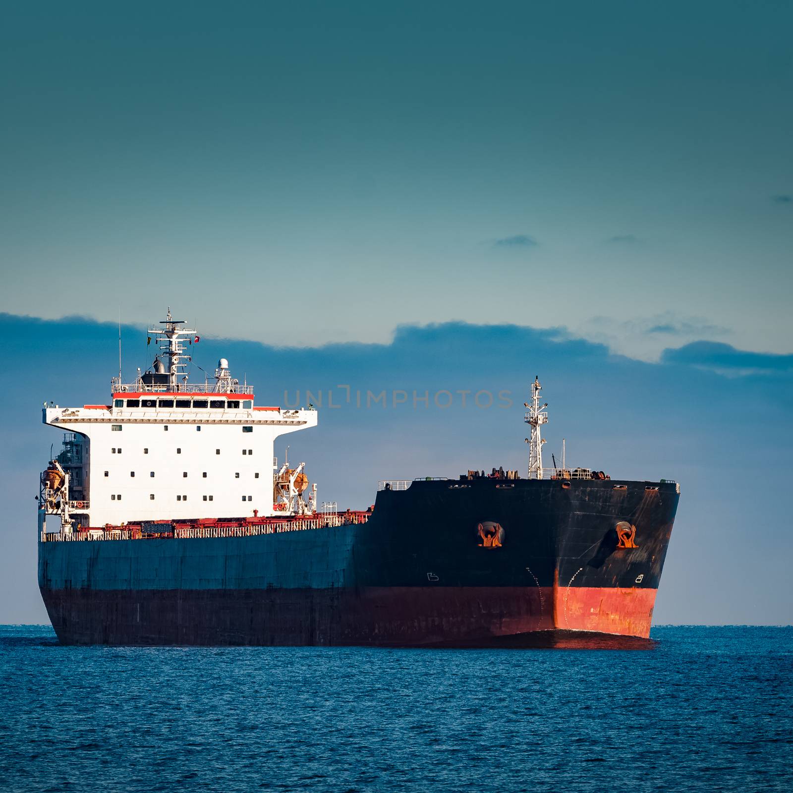 Black cargo ship moving in still Baltic sea water. Riga, Europe