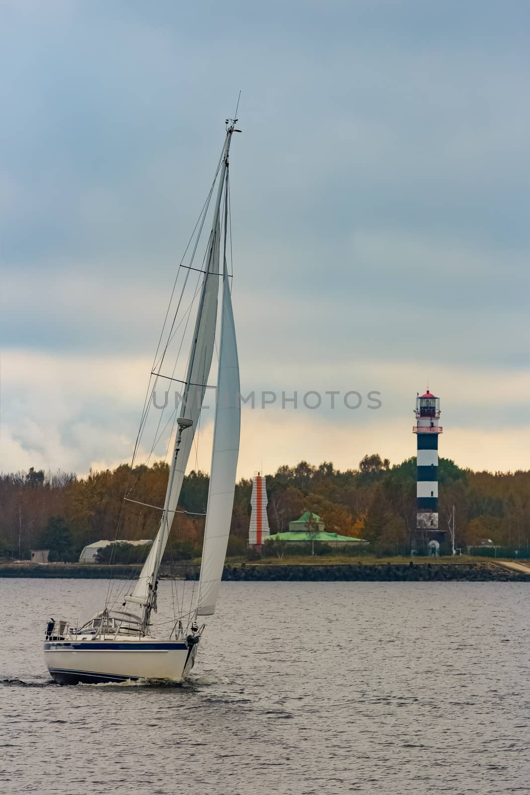 White sailboat traveling past the lighthouse in Riga