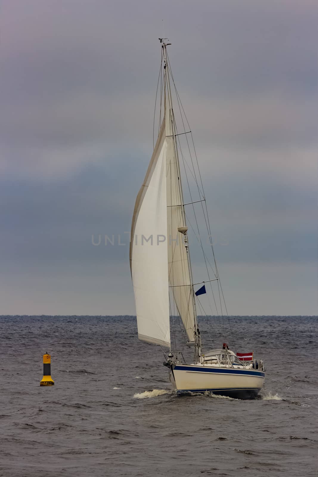 White sailboat traveling in Baltic sea in cloudy day