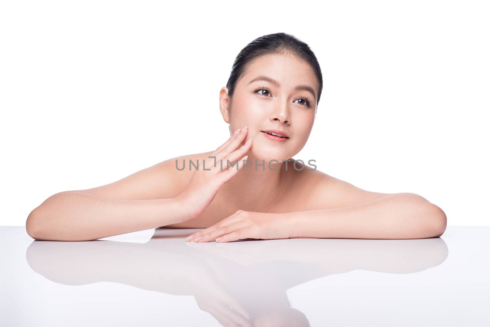 Facial treatment. Beautiful Young Asian Woman with Clean Fresh Skin touch her face .