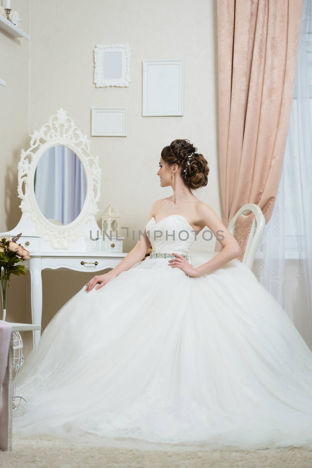 Beautiful young bride in front of the mirror. Portrait with wedding makeup, hairstyle, dress