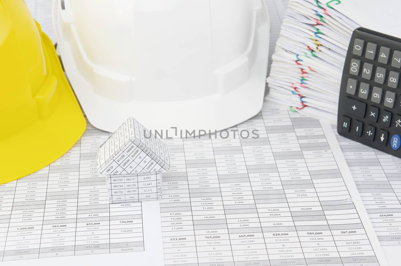 House on finance account have blur white and yellow engineer hat with pile overload document of report and receipt with colorful paperclip with calculator place vertical as background.