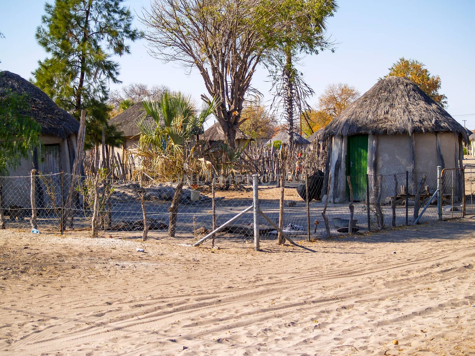 Small African village compound by dusty road, homes and people of Gweta Botswana