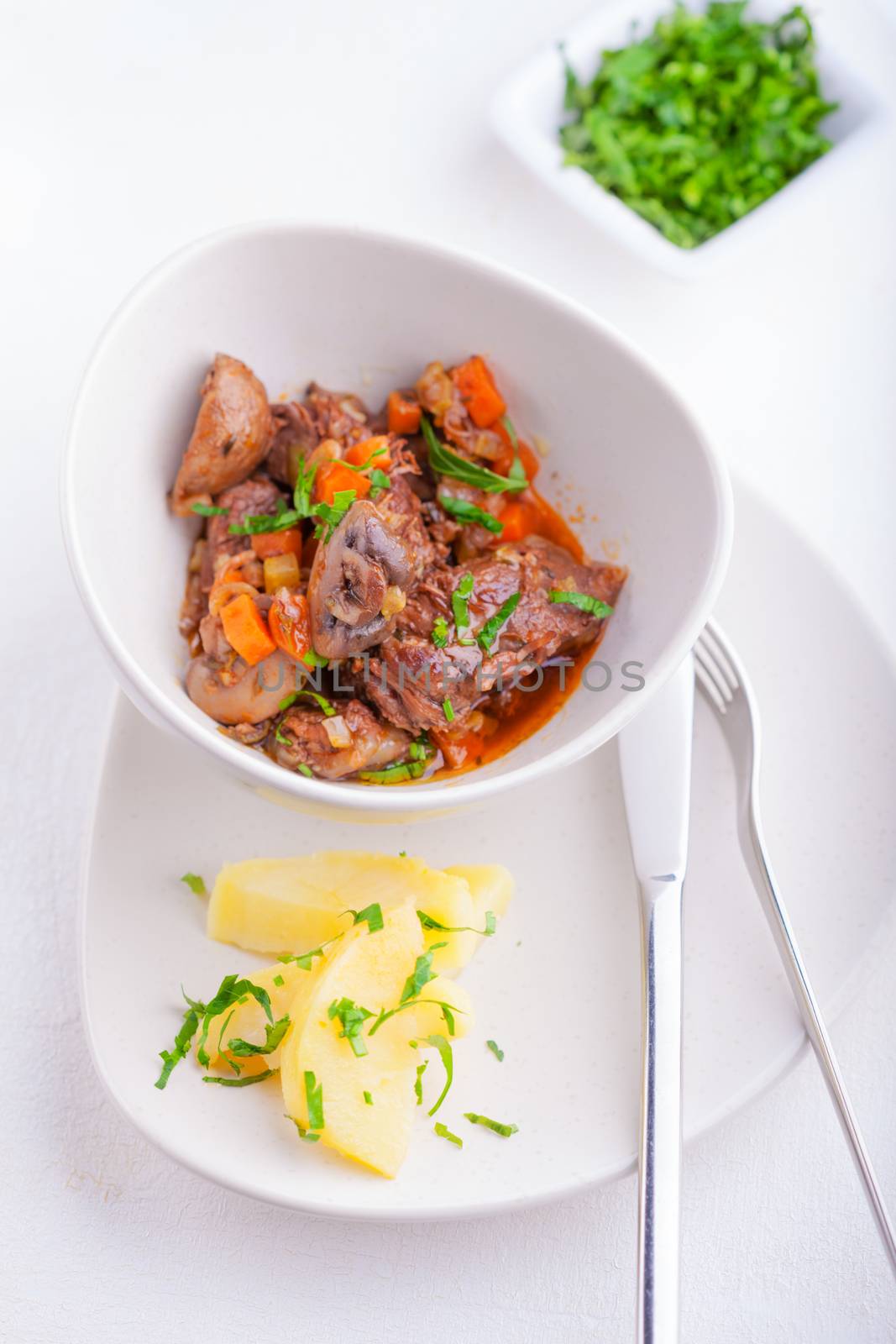 Beef stew being in a slow cooker, garnished with potatoes and champignons