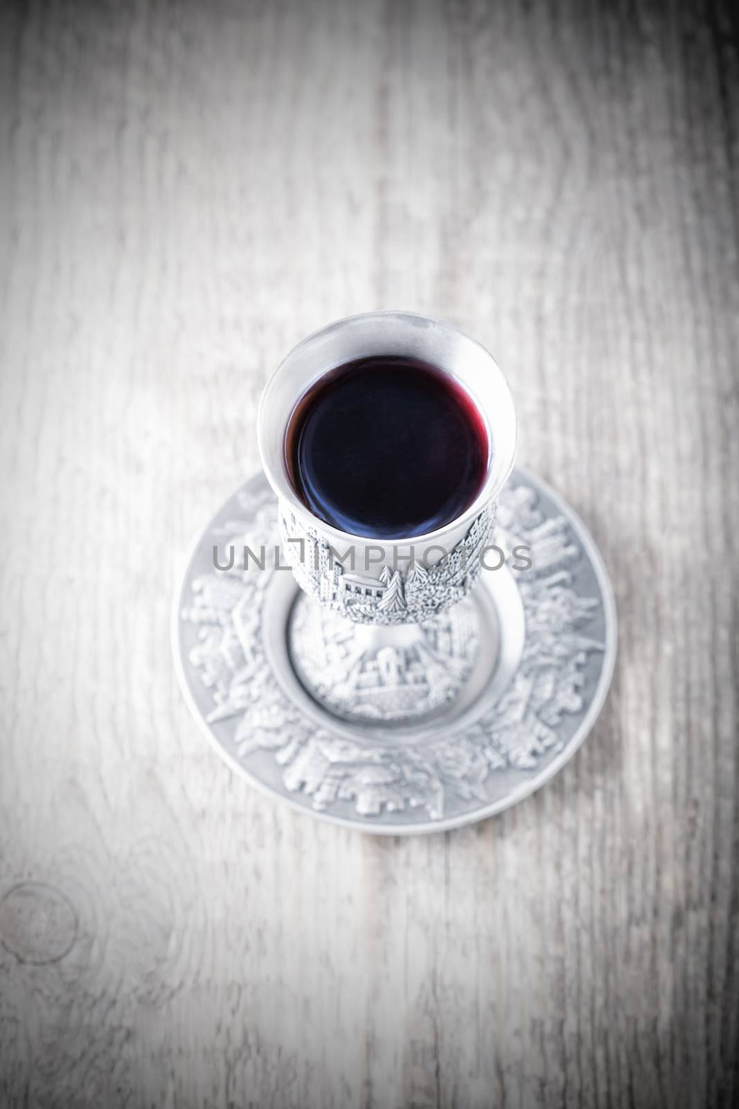 Silver kiddush cup with wine on the wooden table 