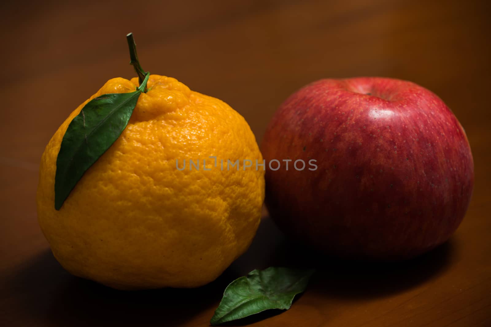 Dekopon Japanese organic orange and red apple on the wooden background