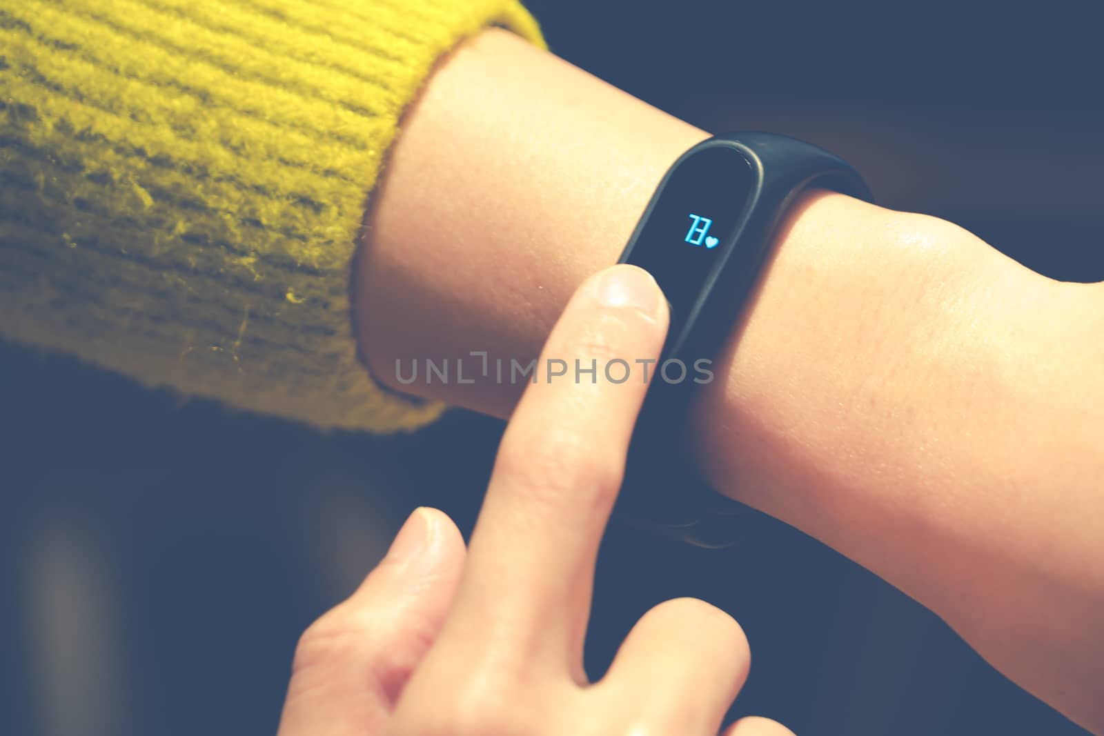 Women touching fitness smart band on her hand by psodaz