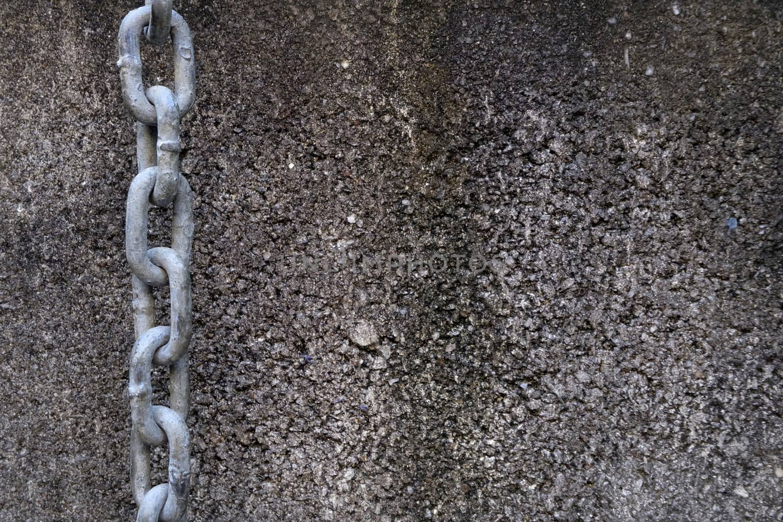 Chain Hanging On A Concrete Wall Background.