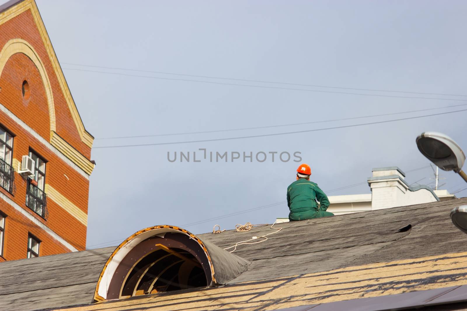 worker in a helmet sit on the building roof