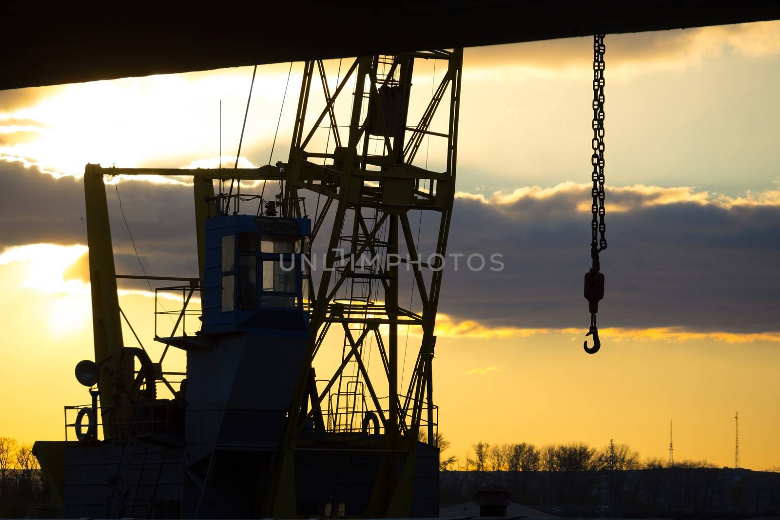 close-up of industrial construction cranes silhouettes over sun sky