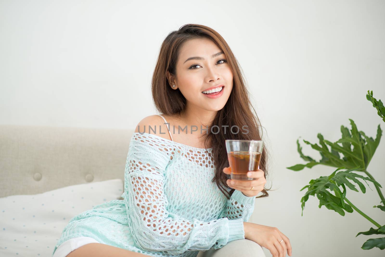 Beautiful young asian woman drinking her morning tea over a brea by makidotvn