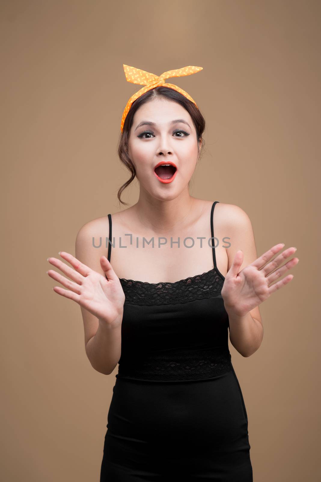 Surprised asian girl with pretty smile in pinup style on yellow background