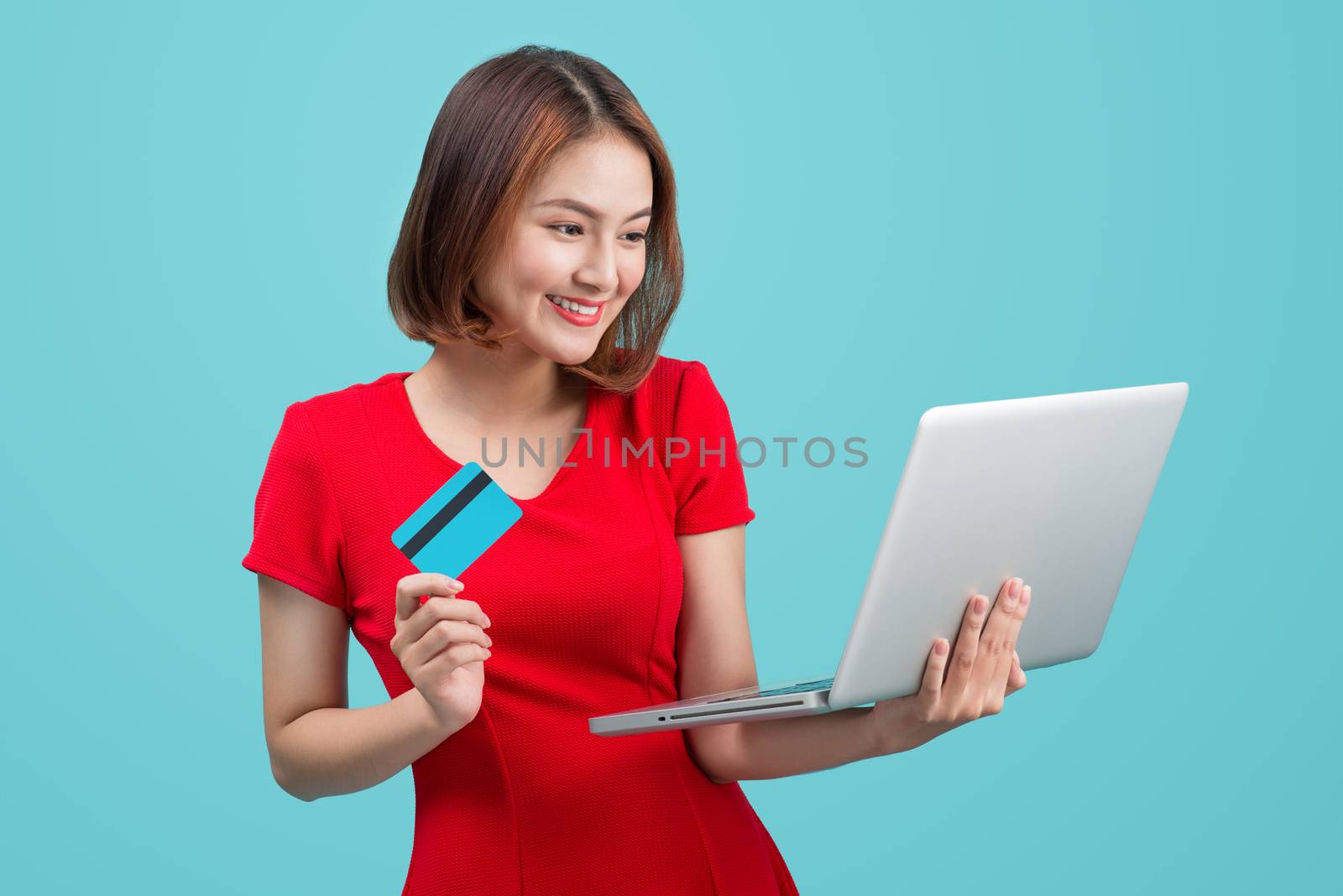 Online shopping. Asian woman holding laptop and credit card read by makidotvn