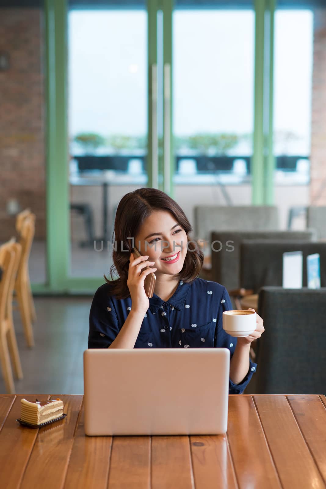 Beautiful cute asian young businesswoman in the cafe, listening to mobile phone and holding coffee mug